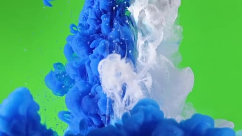 Blue and white inks sprayed together mixing over green screen