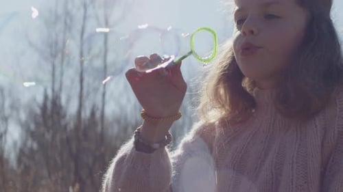 Junges Mädchen bläst Blasen im sonnenbeschienenen Feld