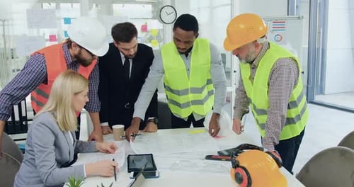 Equipo de ingenieros de una empresa constructora analizando el dibujo de la construcción