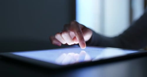 Frau berührt abends den Tablet-Computer zu Hause mit dem Finger