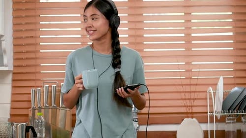 Woman Listening to Music in Kitchen at Home