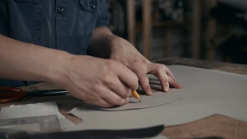 Leatherworker Draws Pattern on Material in Workshop