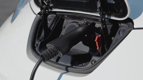Electric Car Charging Batteries with Electricity Through Power Cable on Parking Lot