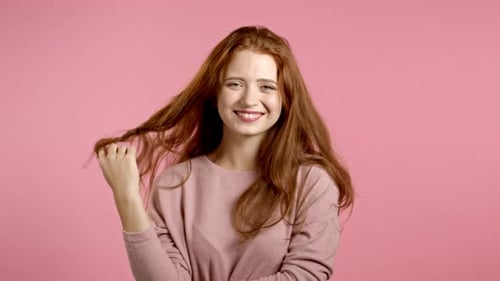 Portrait of Flirting Beautiful Girl on Pink Wall Studio Background. Young Woman Looking To Camera