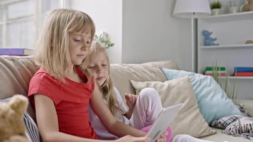Two Young Girls Using Tablet on Couch