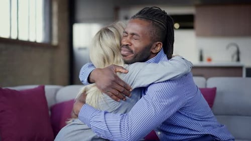 Side View of Loving Interracial Happy Couple Hugging in Slow Motion Sitting on Couch in Living Room