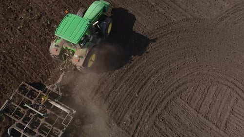 Tractor plows the ground with a plow in the field