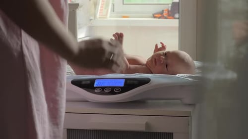 Mother Weighs Baby on Scale Indoors