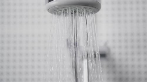 Water Pouring from Silver Shower Head in Bathroom