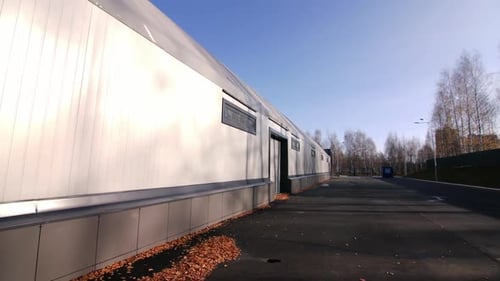 Motion Past Big Grey Warehouse Building in Autumn at Sunset