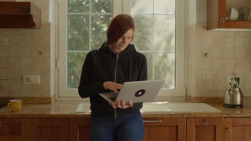 Woman Works on Laptop in Kitchen