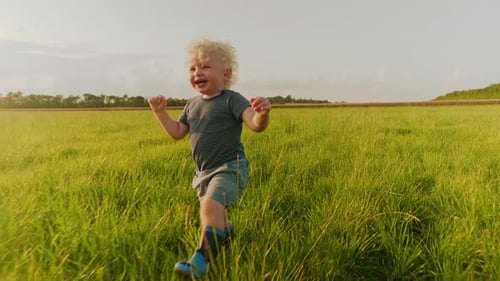 Happy Child Runs Through Green Grassy Field