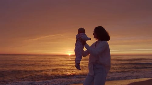 Mother Holds Baby at Sunset on Beach