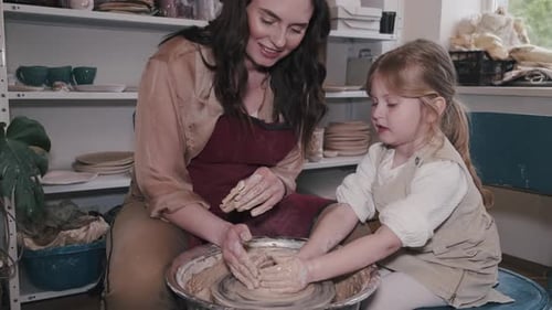 Mother with Daughter Makes Vase in a Pottery Studio