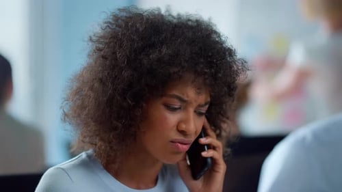 Worried Woman on Phone Call in Busy Office