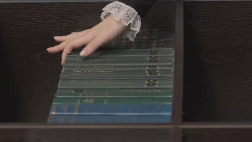 Mano de mujer toma el libro de la estantería