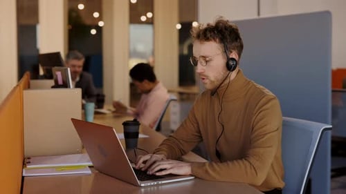 Office Worker Typing on Laptop with Headset
