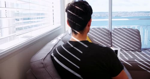 Young Adult Uses Tablet in Sunny Apartment