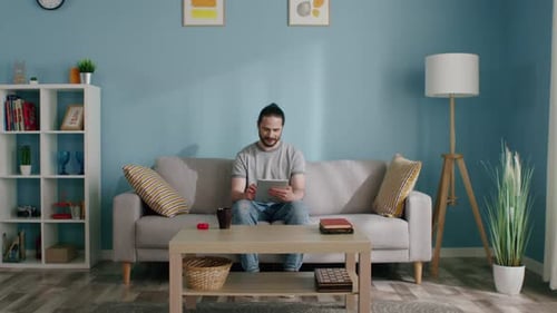 Man Relaxing on Couch Using Tablet in Living Room