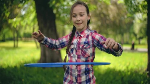 Smiling Girl Playing with Hula Hoop in Park