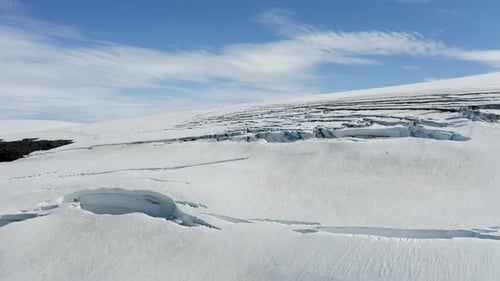 Aerial drone view over snowy glacier surface with cracks, in Langjokull, Iceland