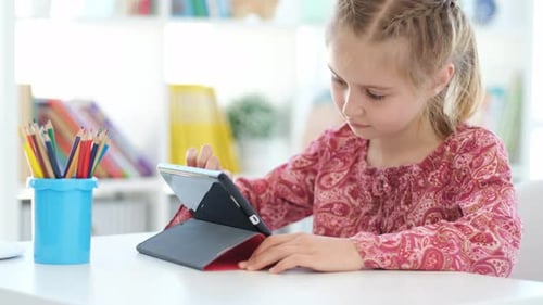 Girl Using Tablet at Table Indoors
