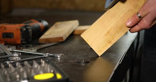 Close up of a worker hand grinds, sanding the wood in workshop