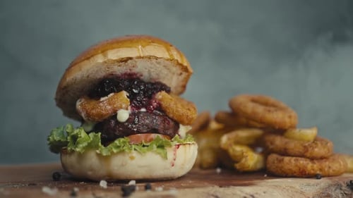 Burger with Onion Rings and Fries on Wood Board