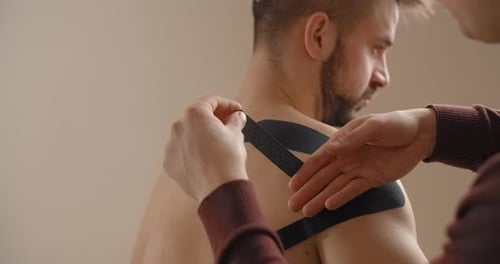 Man Receiving Shoulder Tape Treatment Indoors