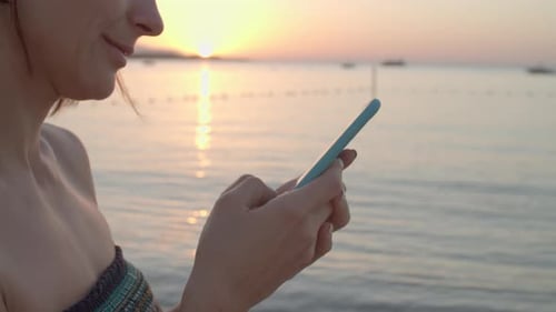 Female Hands Using Mobile Phone By the Sea