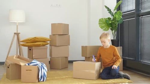 Boy writes on box in bright room