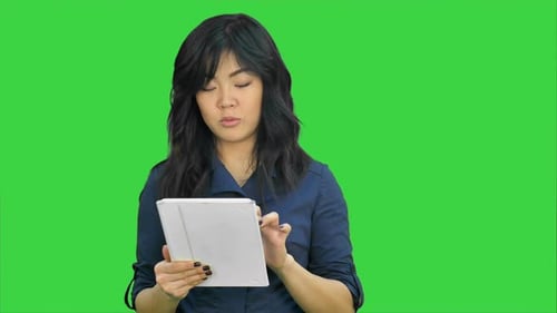 Young Business Woman with Tablet Computer Presenting Project Looking at Camera on a Green Screen