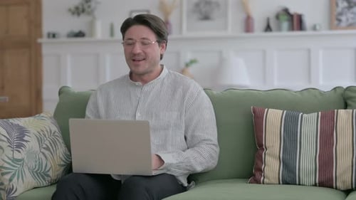 Smiling Man Video Calling On Laptop at Home