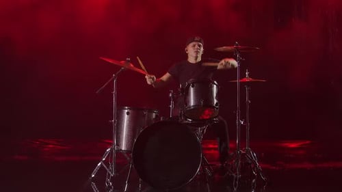 Young Man Enthusiastically Plays the Drum Kit with Drumsticks