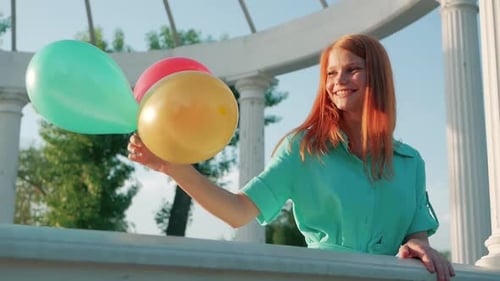 Smiling Woman with Balloons in Urban Park Gazebo