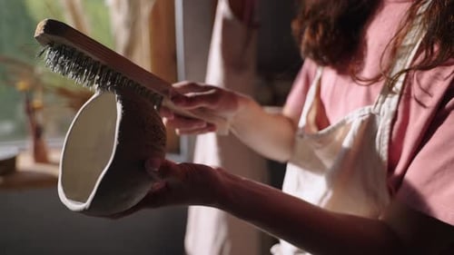 Craftsperson Brushing a Clay Bowl in Pottery Studio