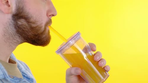 Adult Drinking Beverage with Straw on Yellow Background