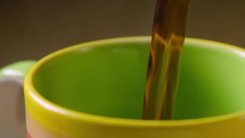 Pouring hot coffee into colorful mug