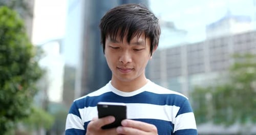 Young Adult Uses Phone in Urban Environment