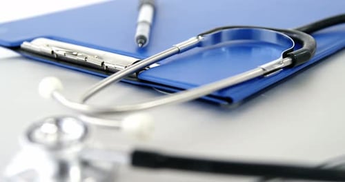 Close-up of folder file and pen with stethoscope