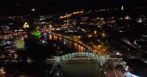 Night aerial view of Bridge of Peace and beautiful cityscape in the center of Tbilisi, Georgia 2022