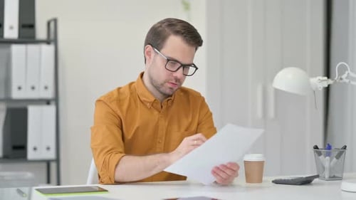 Adult Man Reviews Documents at Bright Desk