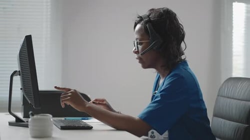 Médica general afroamericana negra con bata blanca sentada en el escritorio en el consultorio del médico