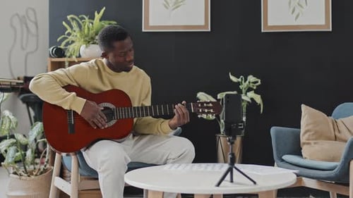 Man Plays Guitar and Looks at Sheet Music