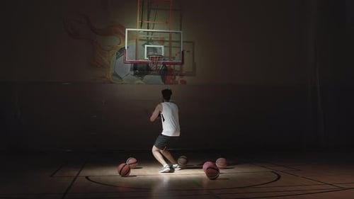 Sportsman Shooting Hoops on Dark Indoor Court