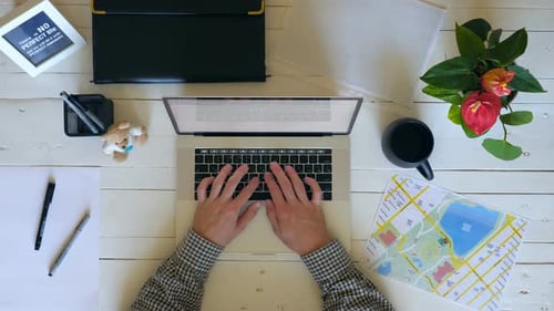 Male Hands Typing Text on Laptop Keyboard at White Wooden Desk