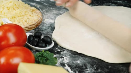 Hands Rolling Pizza Dough with Wooden Rolling Pin