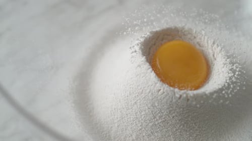 Egg falls on a pile of flour. Slow Motion.