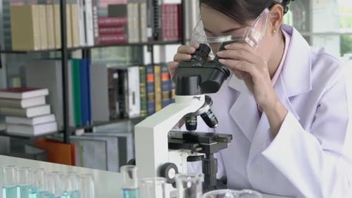 Woman is looking through microscope in laboratory