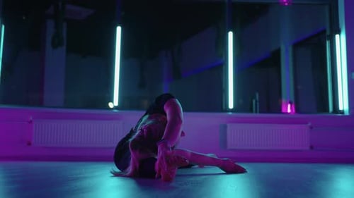 Woman is Doing Stretching Exercises in Fitness Hall Sitting on Floor and Leaning Body to Side
